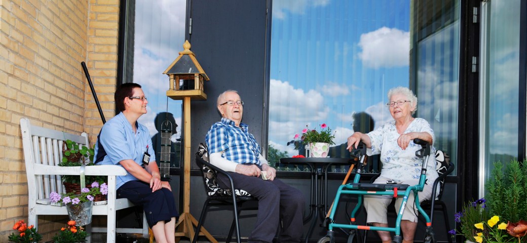 To beboere på Æblelunden hygger på deres terrasse med personale