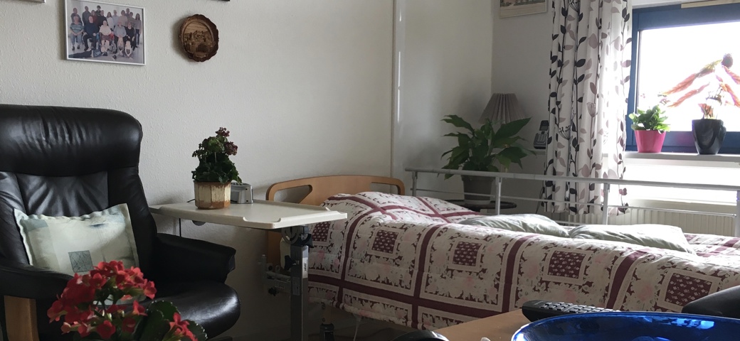 Birkebjergcentret bolig 2 sal - viser seng med lænestol ved siden af.