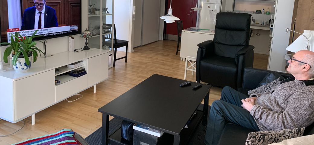 Mand sidder og ser fjernsyn i sin bolig på Æblelunden
