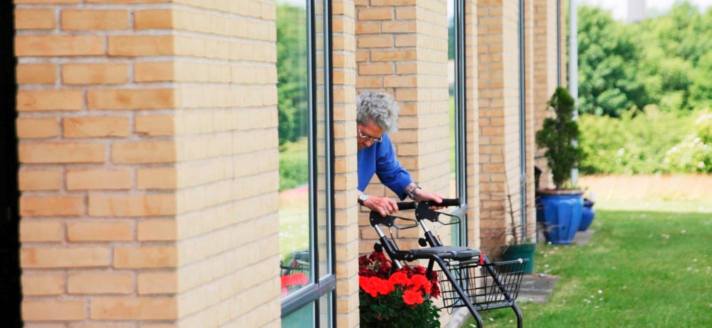 Kvinde kommer ud på terrassen med rollator fra egen bolig i Æblelunden