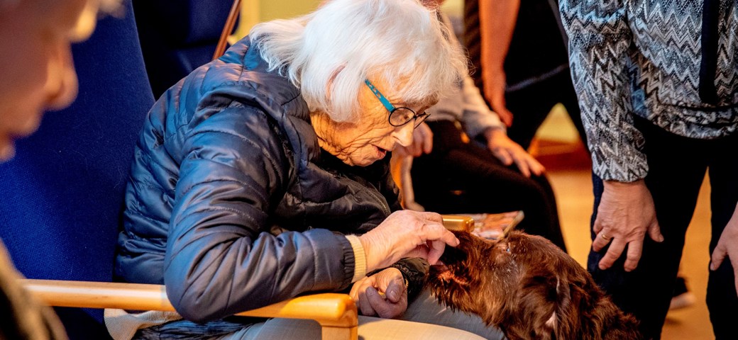 Dame sidder med besøgshund på daghjemmet Korinthvej