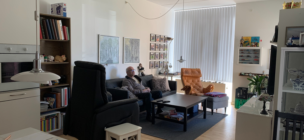 Mand sidder og ser fjernsyn i sin bolig, som viser hans stue i sin bolig på Æblelunden